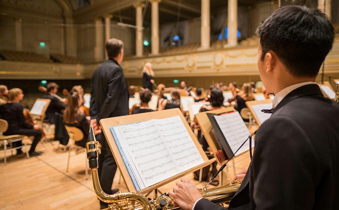 Mann der ein Instrument hält und auf einen Notenständer schaut